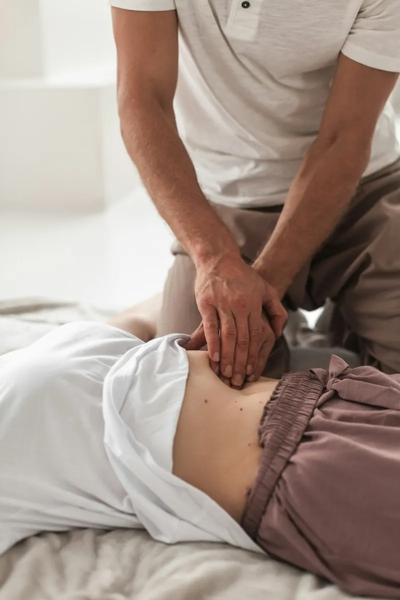 Practitioner assessing the abdomen and low back of a client lying on a treatment table