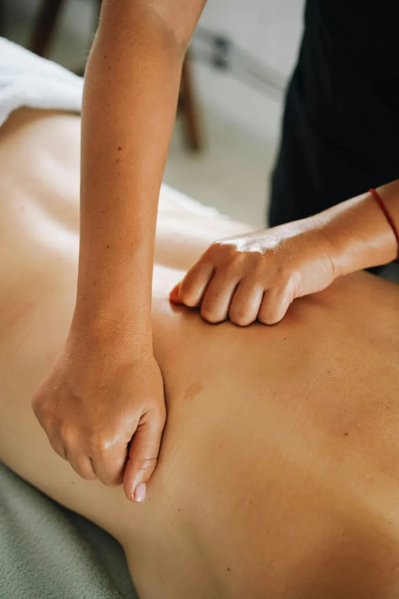 Therapist's hands applying slow, sustained myofascial release pressure along a client's back